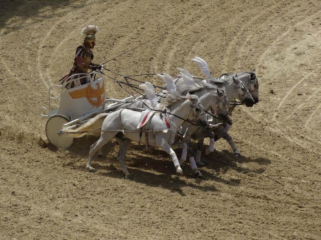 A charioteer in ancient Roman armor drives a team of four horses