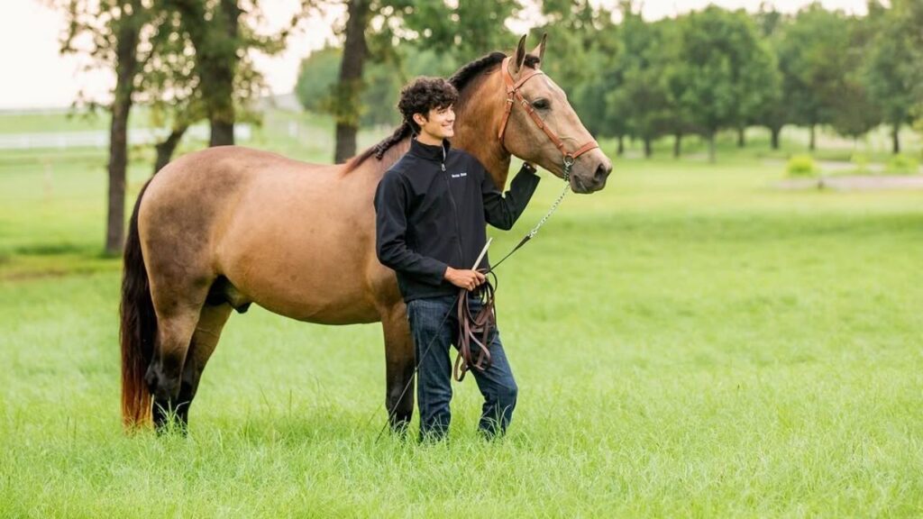 A young rider stands beside a chestnut horse