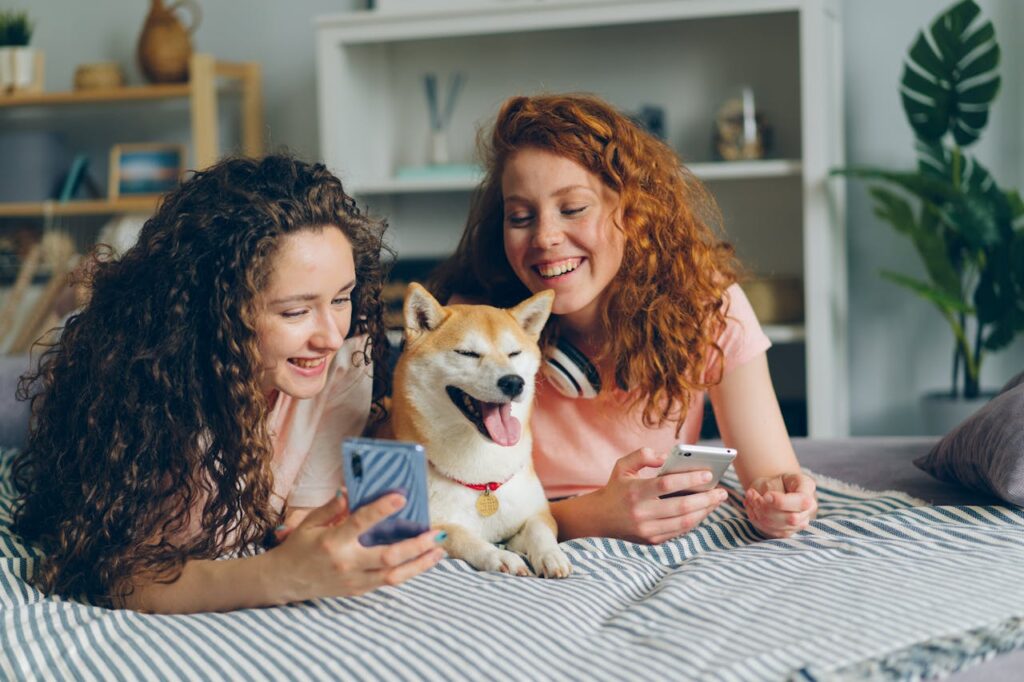 A Shiba Inu dog is happily sitting between two girls