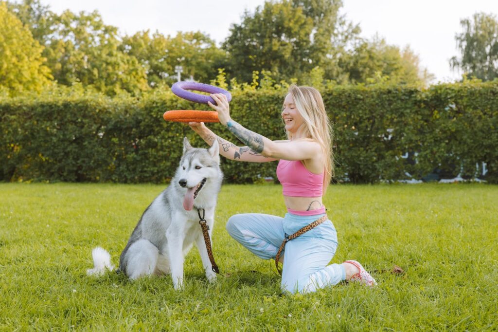 Smiling Blonde Woman Playing with Dog in Garden