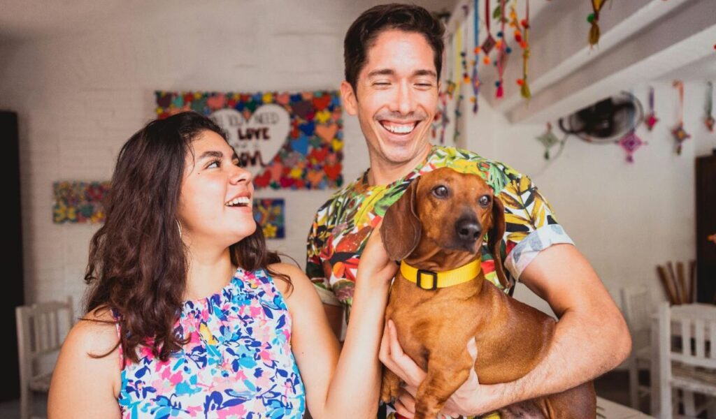 Smiling couple holding a Dachshund.