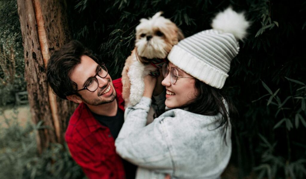 Smiling couple holding a Shih Tzu.
