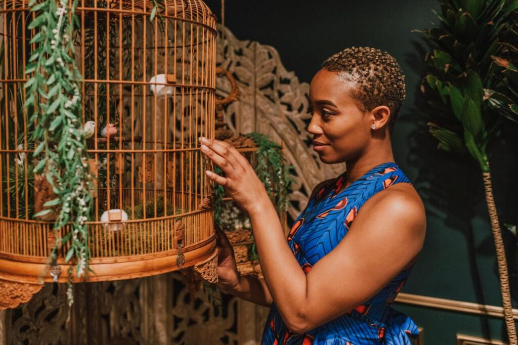 Woman admiring birds inside decorative cage.