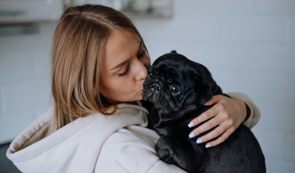 woman kissing a black bulldog
