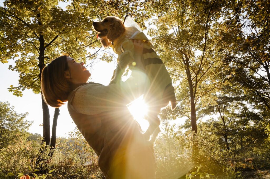 woman holding up a Cavalier King Charles Spaniel in a forest