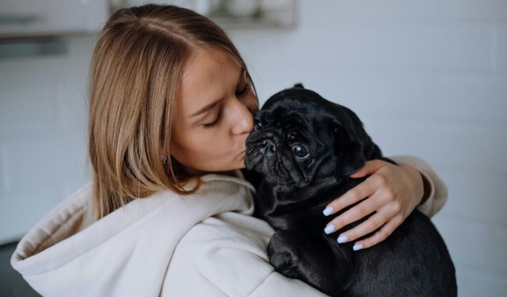 Woman kissing a pug.