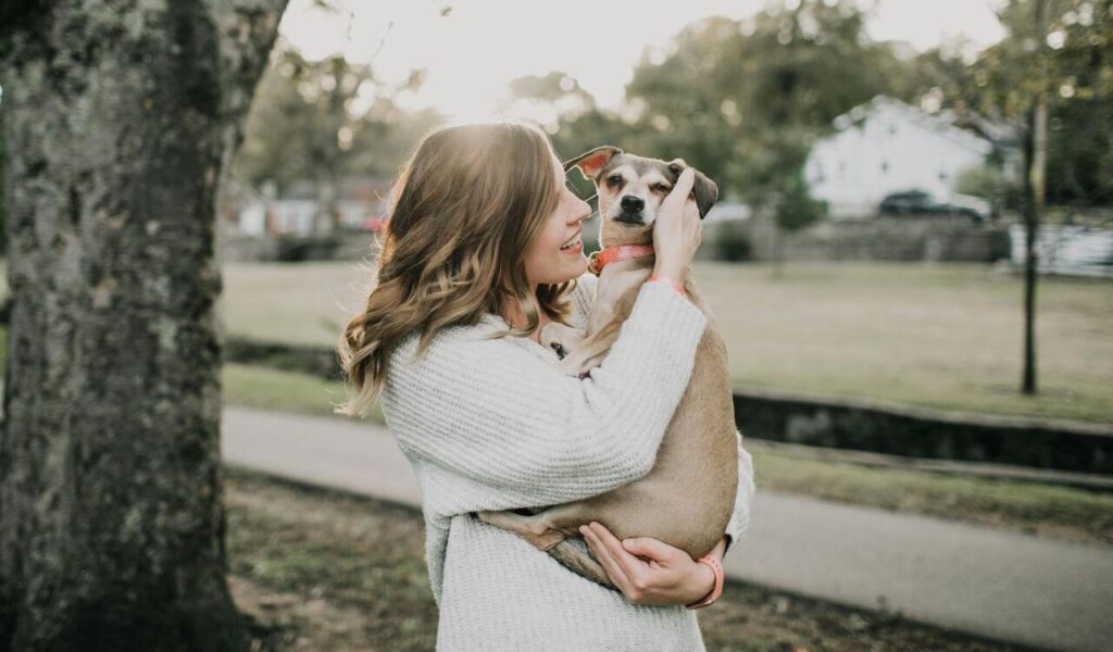 woman holding a small dog outdoors
