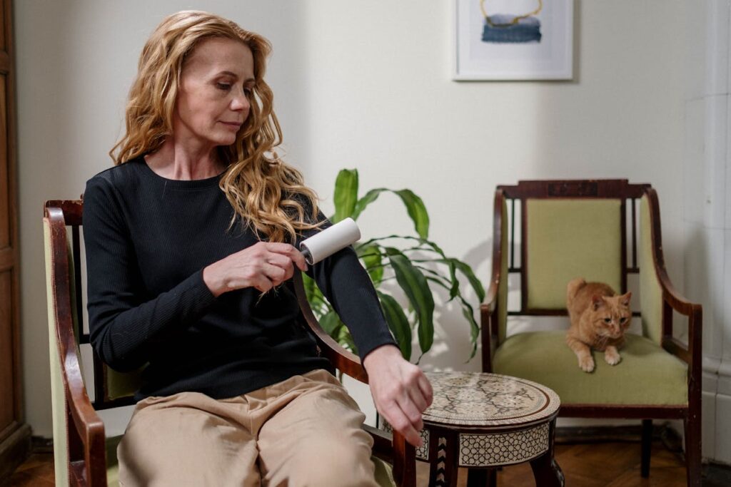 Woman using lint roller with ginger cat behind