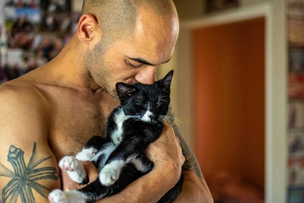 Man affectionately cuddling a relaxed cat.