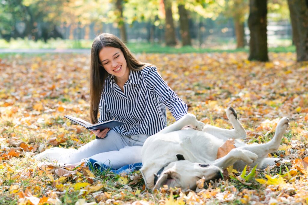 Adult woman petting her Labrador retriever in the park