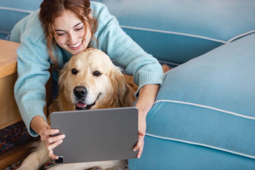 Medium shot woman holding tablet infront of golden retriever