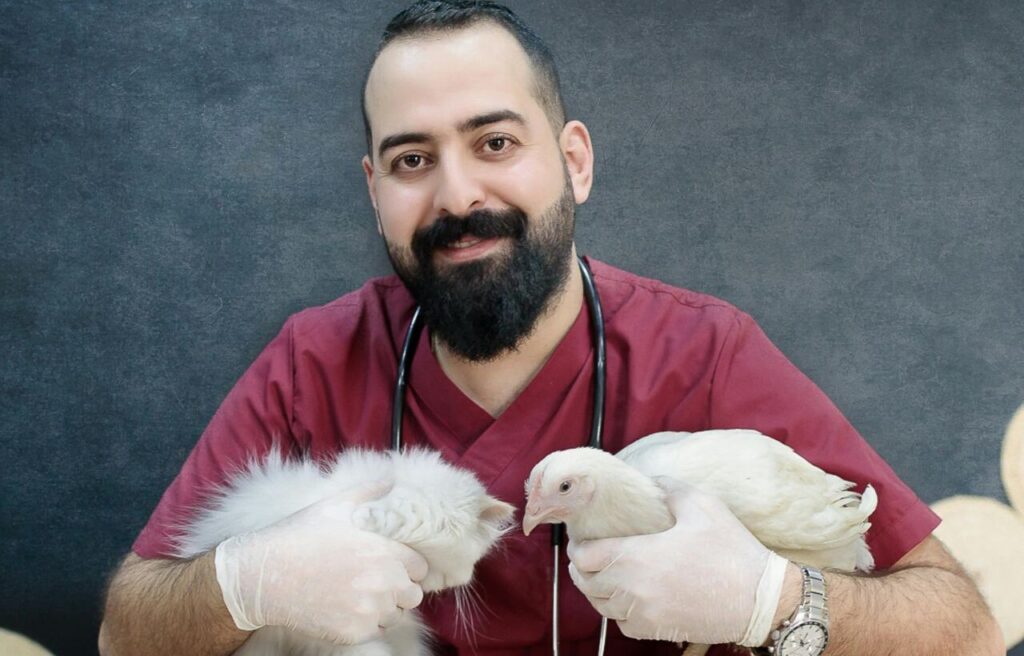 Veterinarian holding a cat and chicken, smiling.