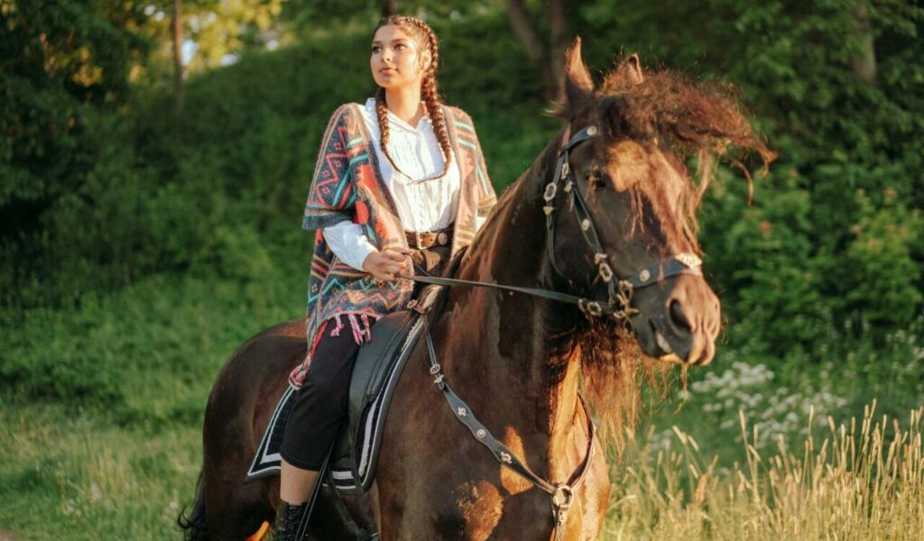 Woman riding a horse, wearing a colorful poncho.