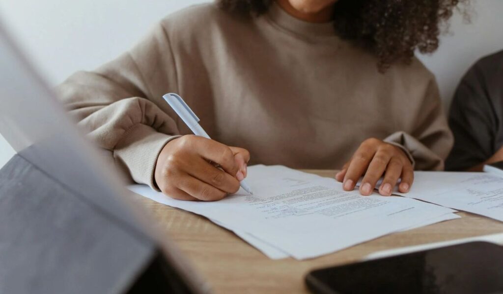Close-Up Shot of a Person Writing on a Paper Using a Ballpen