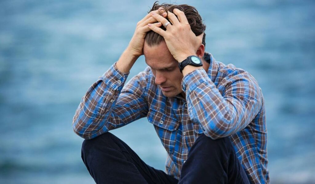 Man in Blue and Brown Plaid Dress Shirt Touching His Hair