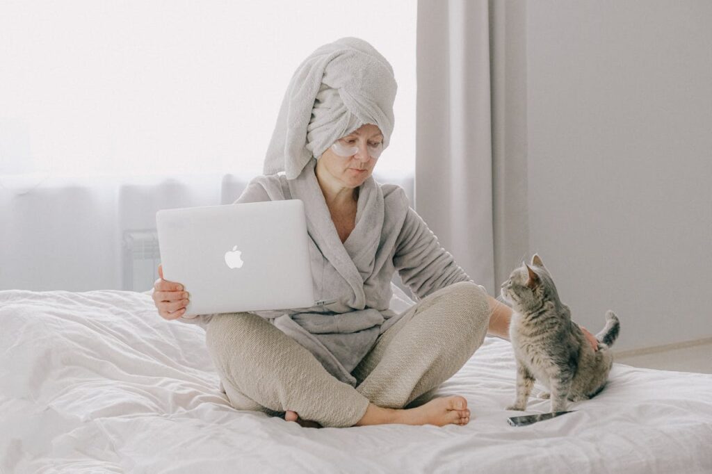 Woman in Gray Bathrobe Using MacBook beside cat