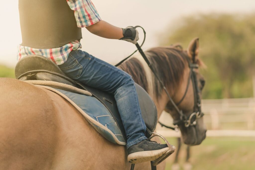 Kid learning to ride horse