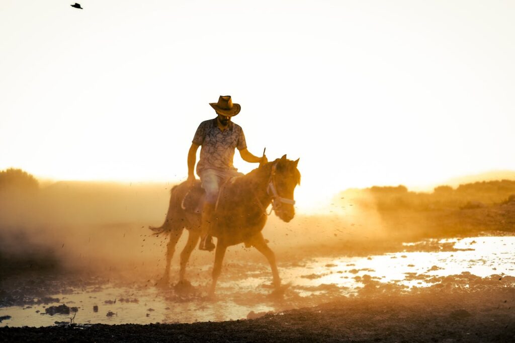 A man riding a horse through a muddy field