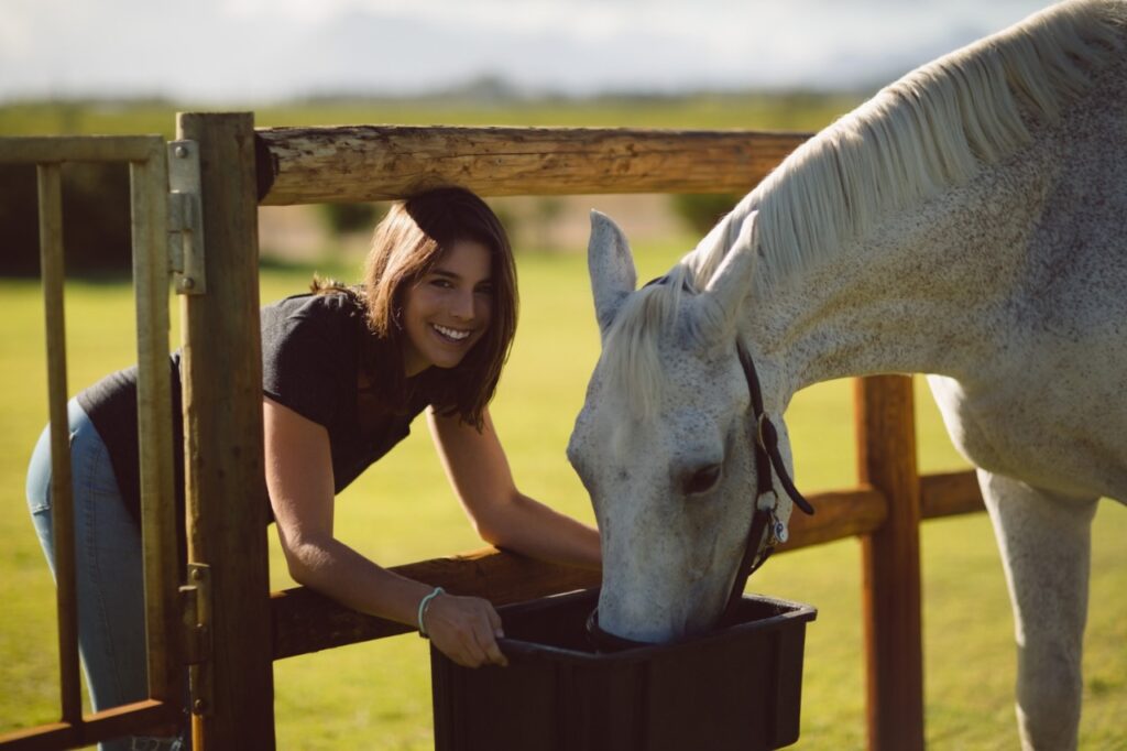beautiful woman feeding horse in farmland
