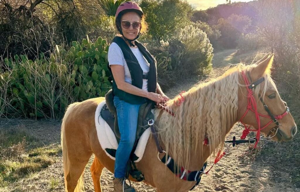 Woman riding a Missouri Fox Trotter on a sunny trail.