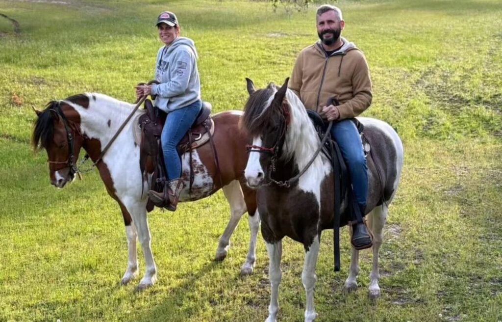 Two riders on Paso Fino horses in a meadow.