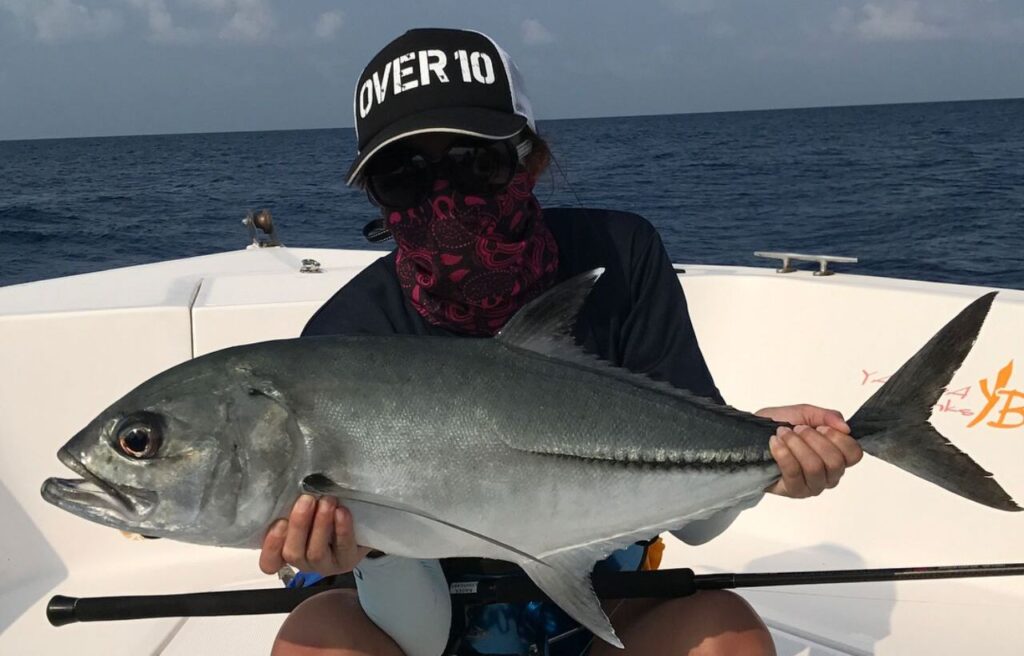 Angler on boat holding bigeye trevally.